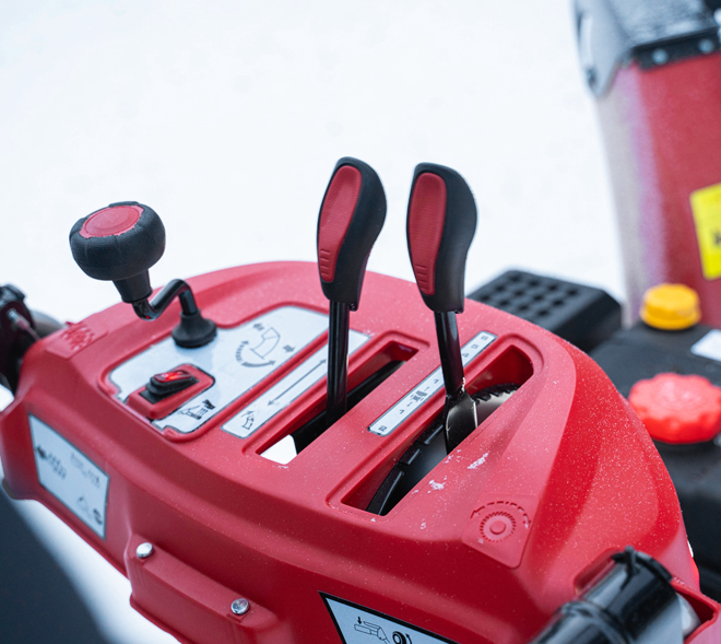 <b>Многофункциональная панель оператора</b>. 
Snow Line 560 - переключение скоростей. Направление выбросом осуществляется рукояткой под панелью.
На моделях Arctic Line на панель оператора, помимо управлением КПП, выведены управление выбросом, кнопки включения подогрева рукояток и освещением.